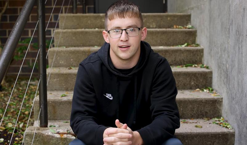 Jacob Perks, sitting outside the Hennessey Gym at Mount Mercy